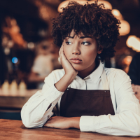 a young woman looking perplexed sitting alone at a table