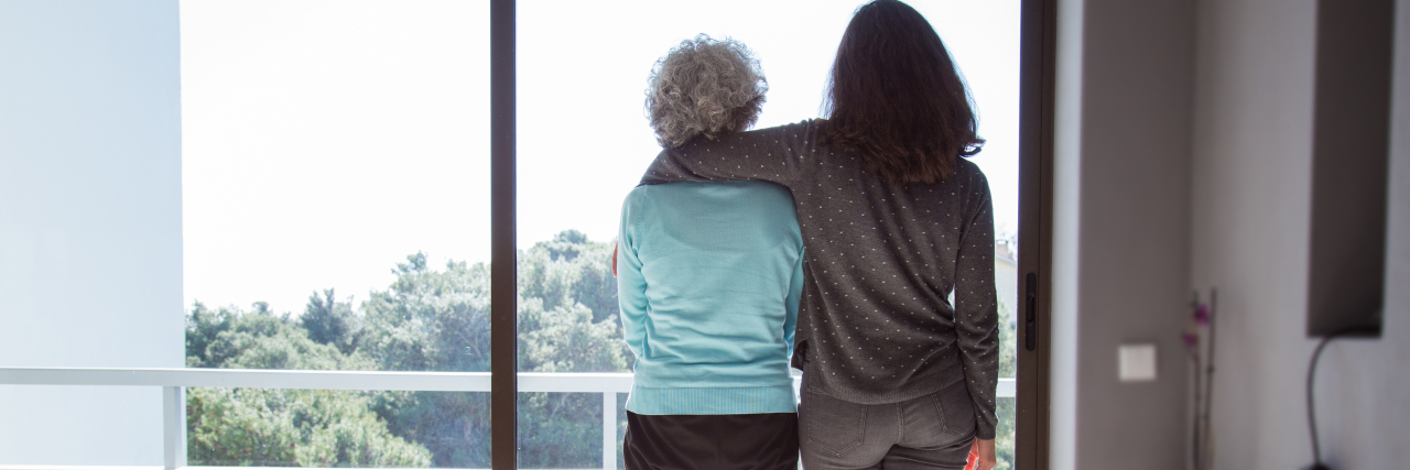 a young woman looking at the window with her arm around an older woman
