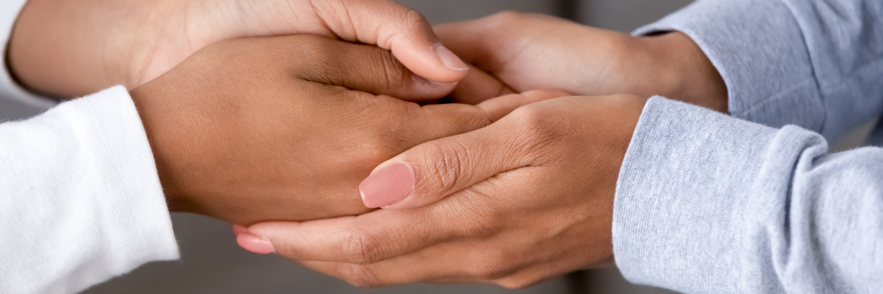 Navigating a Chronic Illness as an Empath Woman clasping another woman's hands, offering comfort.