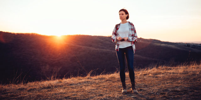 8 Things I Learned After an Anxiety Attack Led to 12 Days in a Partial Hospitalization Program  middle-aged woman in a flannel shirt and jeans standing on a hill during sunset looking out