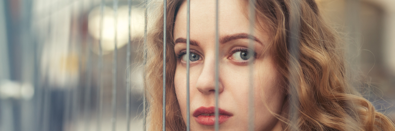 young woman behind bars looking at the camera