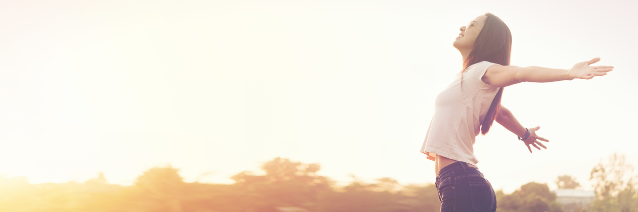 Why People With Chronic Illness Don't Take 'Normal' Days For Granted a young woman with her arms extended open as she smiles in the outdoors