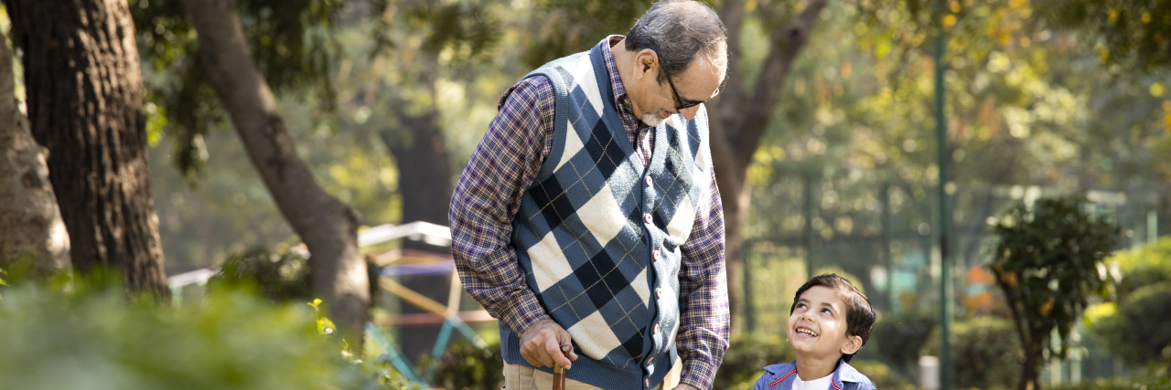 How a Joke Caused Me to Think About My Mental Illness Differently grandfather and grandson walking in the park hand in hand, the grandson smiling to the grandad