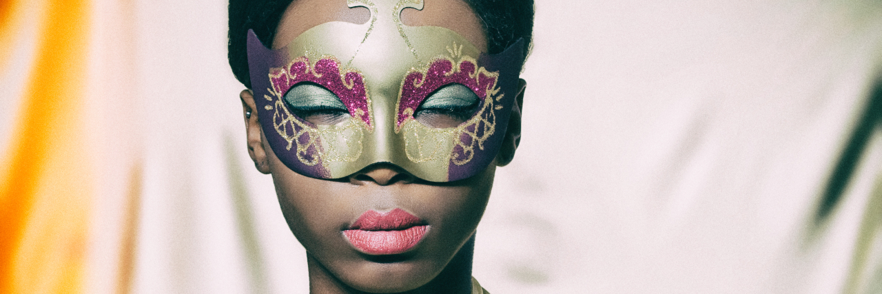 Why I Still Mask My Autism During Black History Month Black woman wearing a golden carnival mask.