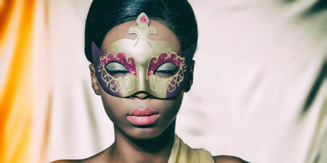 Black woman wearing a golden carnival mask.