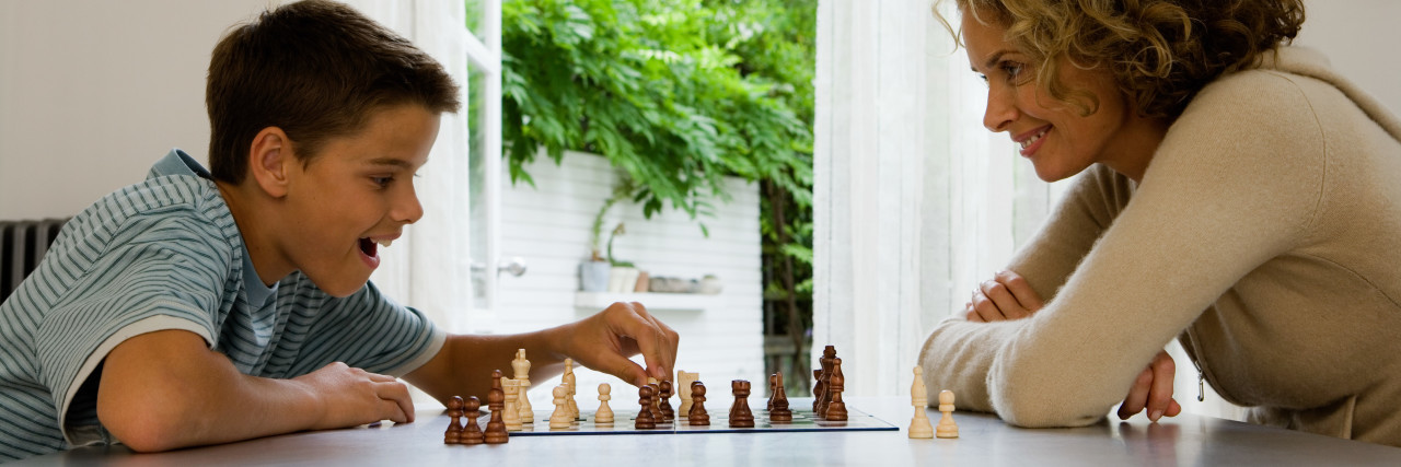 How Expecting Eye Contact Causes Stress for Children With Autism Mother and son playing chess.