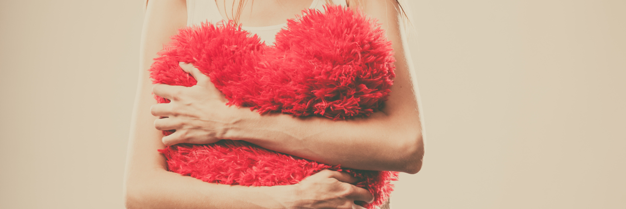 Woman holding a heart pillow.