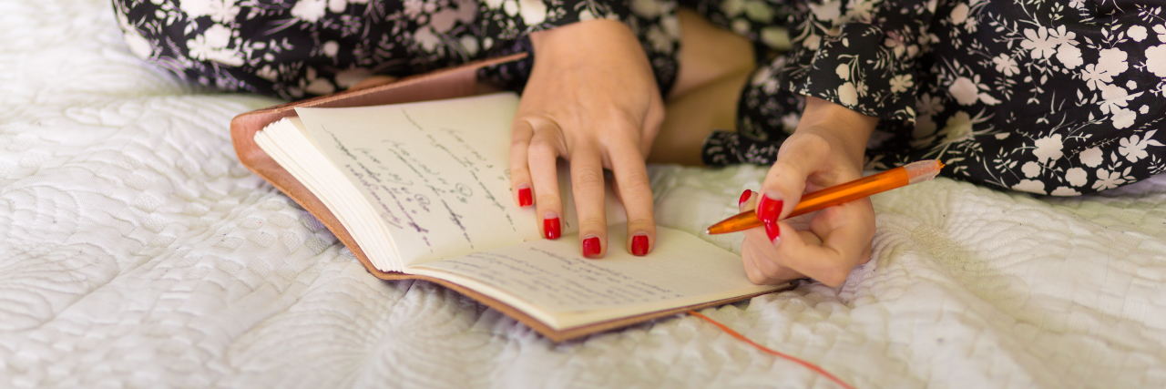 My Complicated Relationship With Sleep as Someone With Fibromyalgia Woman writing in her diary in bed.