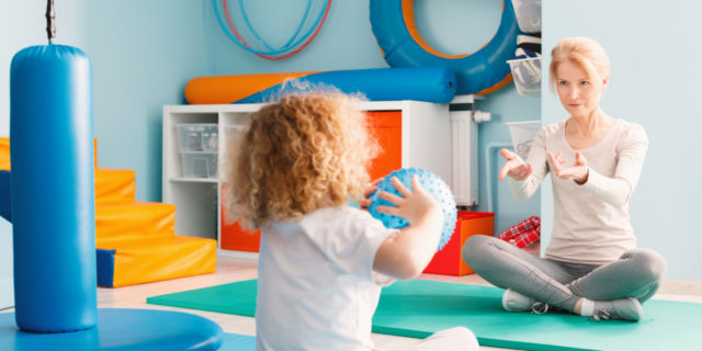 It's Time to End the Stigma Around Early Intervention Child playing with therapist using a ball.
