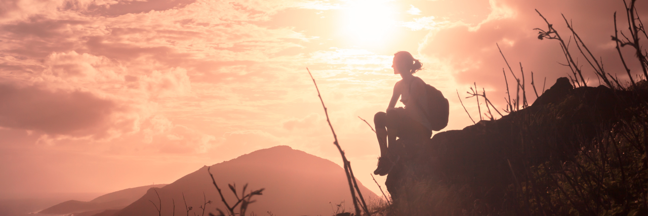 How to Build Resilience for Life With Chronic Illness a woman sitting down watching the sunset outdoors