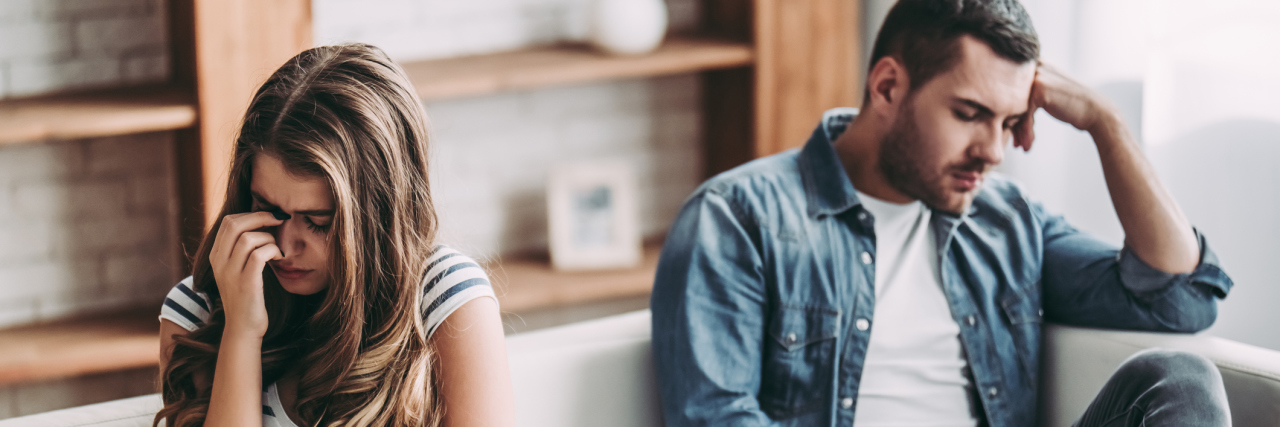 The Many Faces of Domestic Violence Upset couple at home. Handsome man and beautiful young woman are having quarrel. Sitting on sofa together. Family problems.