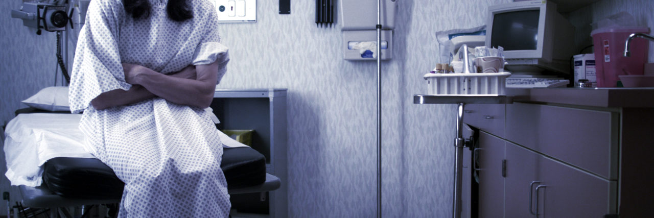 a woman sitting in a doctor's office, waiting to be examined