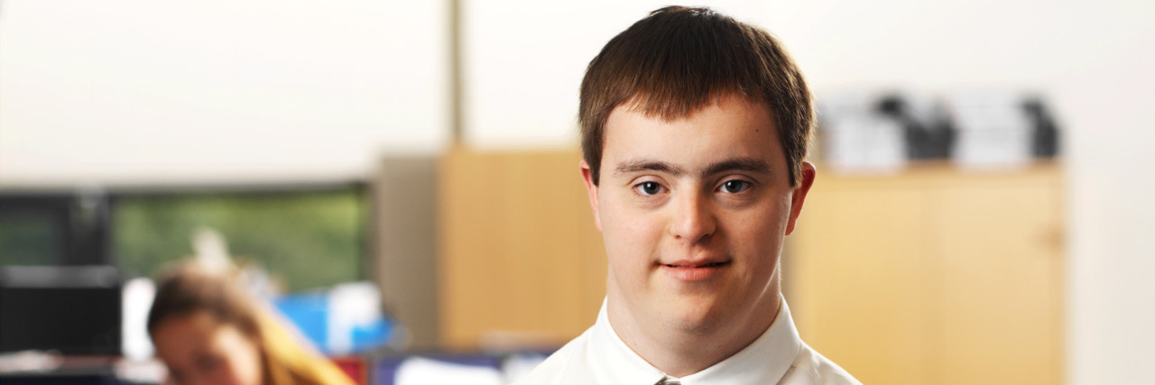 Why Leaders Must Stop Forgetting People With Disabilities Man with Down syndrome working in an office.