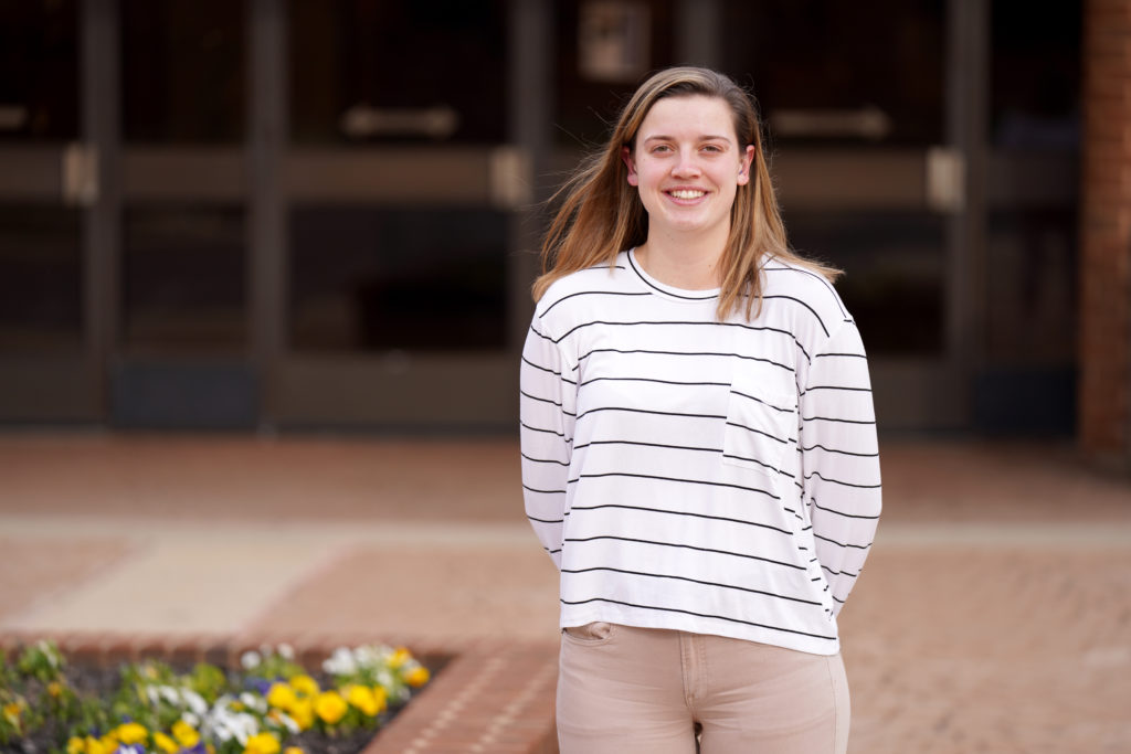 Hannah Neild in a white and black stripped shirt in front of a building