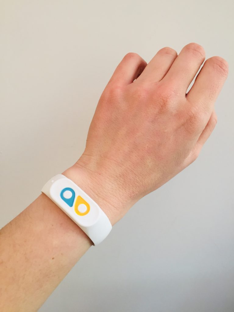 screenshot of Moodbeam One mood tracker, a white wrist bracelet with a blue icon and yellow icon, worn on the contributor's arm