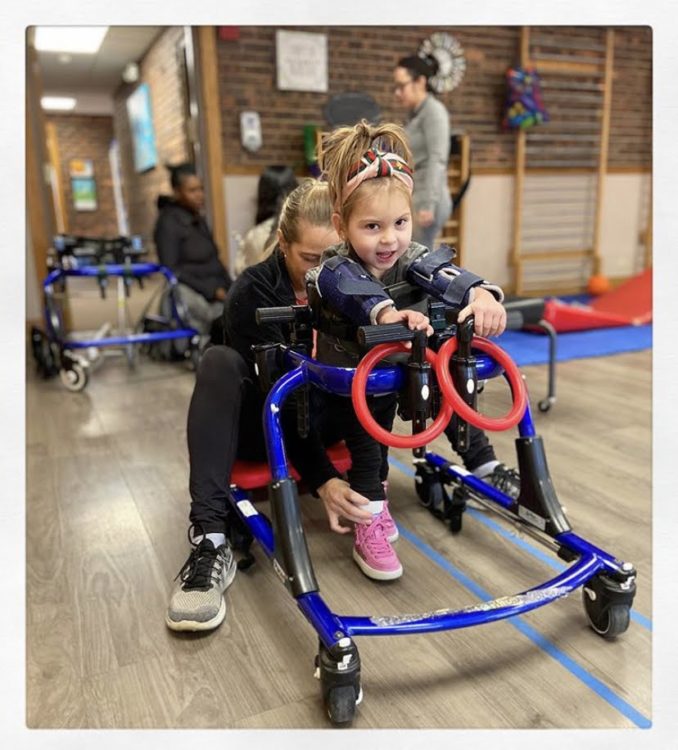 a girl with a disability in therapy working on walking.
