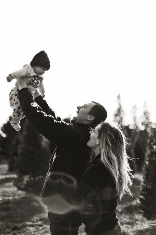 A black and white picture of a playful, young couple and their toddler.