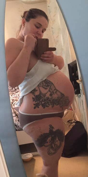 The author, pregnant, showing her tattoos in the mirror