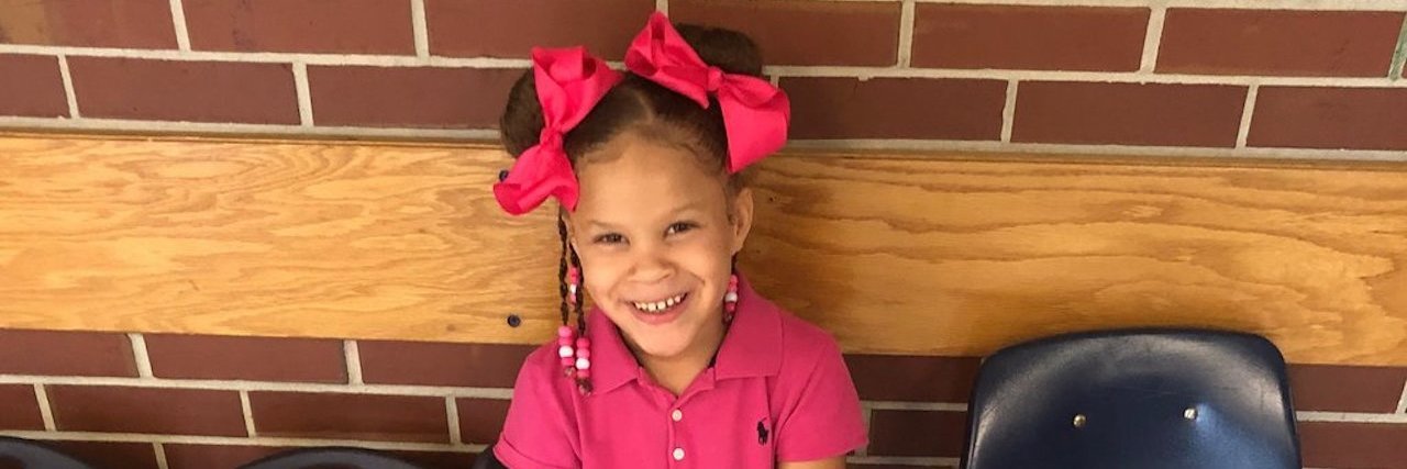 6-year-old Nadia King wearing a pink dress and pink bows in her pigtails