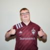 Special Olympian and soccer player Scotty Stephens, a white man with Down syndrome, wearing a maroon jersey and giving two thumbs up