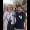 a young woman and a man at a sporting event in Yankees gear posing for a picture