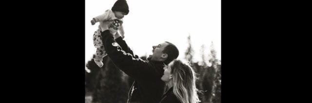 A black and white picture of a playful, young couple and their toddler.