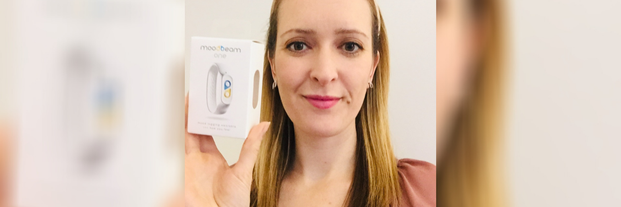 What It's Like To Use a Mood Tracker Device for Mental Health photo of contributor holding a box for the moodbeam one mood tracker