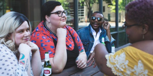 We Need to End Fatphobia in Eating Disorder Awareness and Recovery photo of several plus-size people of different ethnicities sitting at table talking and drinking beer