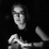 photo of woman sat mostly in darkness, with serious expression