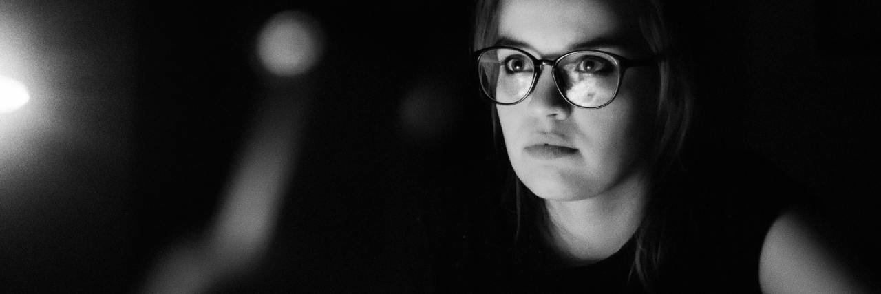 What to Do If You're Dealing With an Argumentative Doctor photo of woman sat mostly in darkness, with serious expression