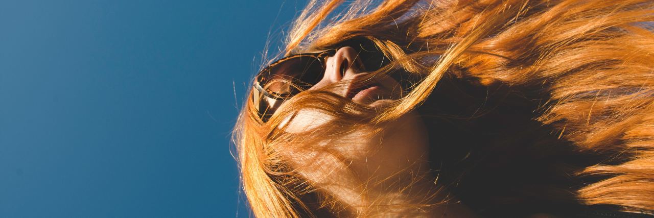 looking up at woman with red hair and sunglasses