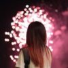 Woman looking at a red firework exploding in the sky