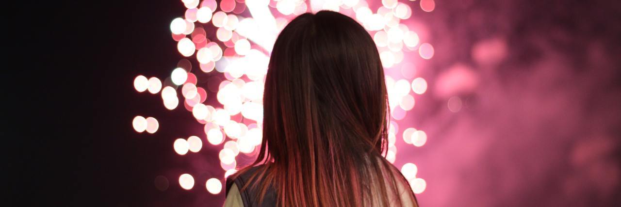 What Mania Feels Like When You Have Borderline Personality Disorder Woman looking at a red firework exploding in the sky