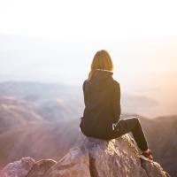 Woman watching the sunset from the top of a mountain.