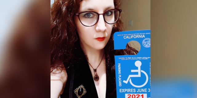 Amelia holding her disability parking placard.