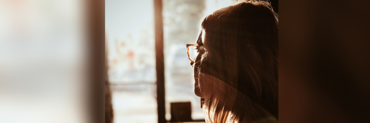 Woman wearing glasses and looking outside a window
