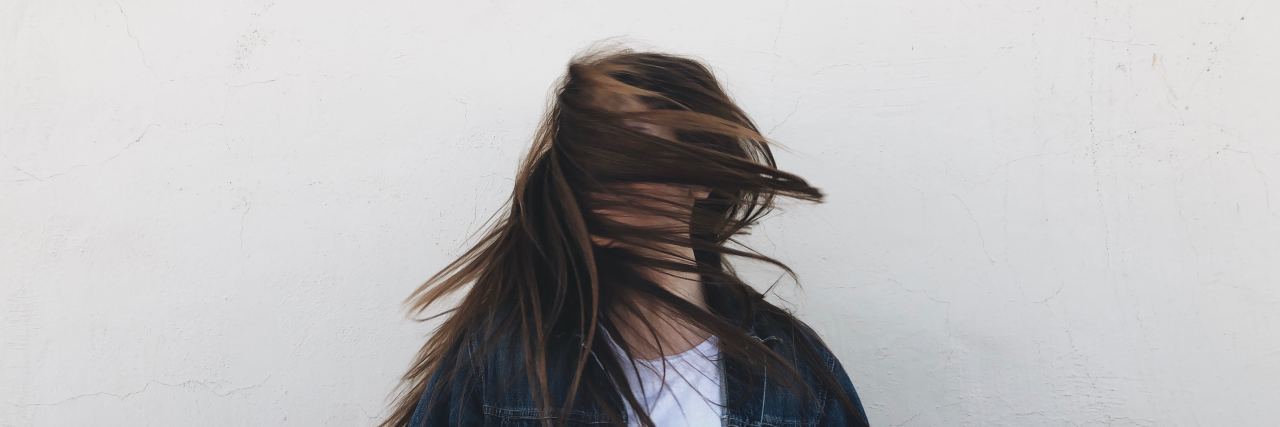 The Importance of Medicine and Correct Diagnosis for Bipolar Disorder woman in a white shirt and jean jacket with brown hair blowing across her face