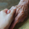 A young person's hand holding an older person's hand