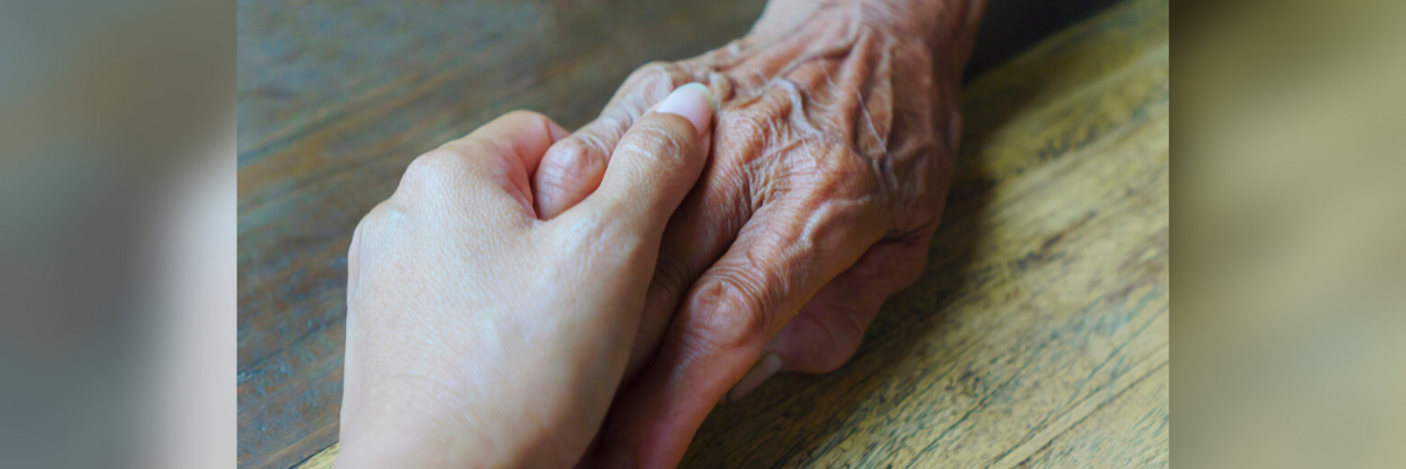 A young person's hand holding an older person's hand
