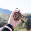 photo of person's hand holding out compass in dusty blurred landscape