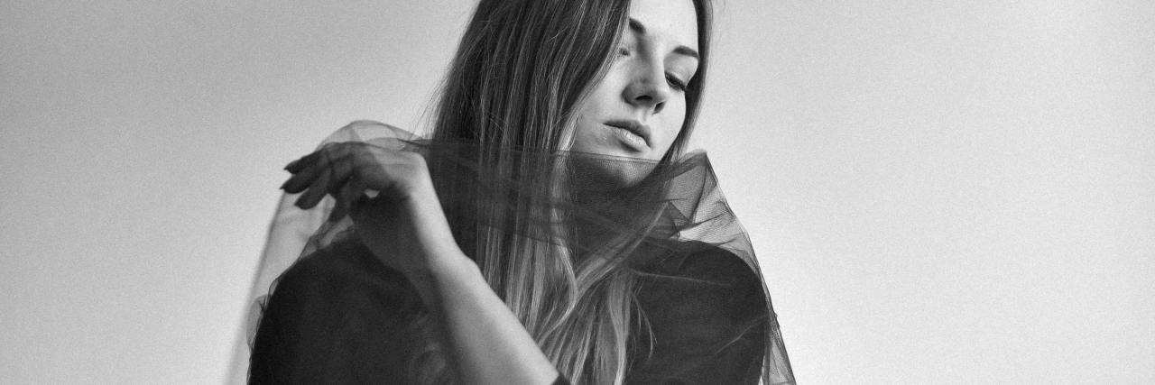 Living With an Eating Disorder Started by Stomach Pain A woman wearing a black top, with sheer fabric wrapped around her body