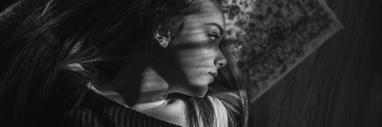 Having a Positive Eating Disorder Treatment Experience After Negative black and white photo of woman lying on floor on patterned rug while sunlight falls across her face