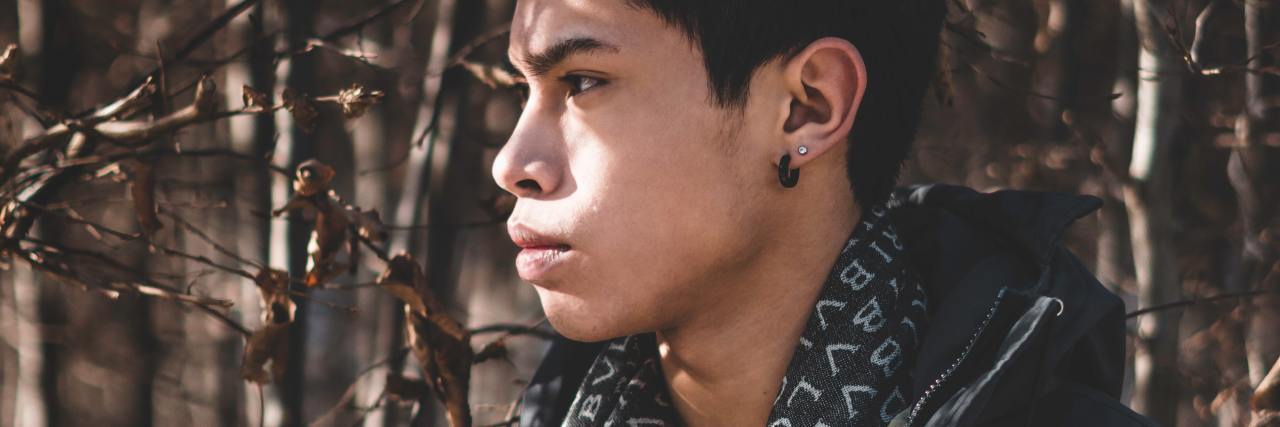 Wearing Baggy Clothing Due to Self-Harm, Body Image, Eating Disorder photo of man wearing heavy baggy clothes, standing in trees with sunlight on his face