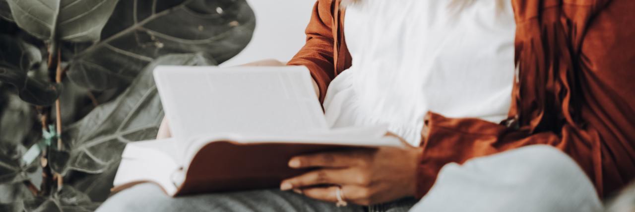 neck-down photo of a woman sitting down, reading her bible