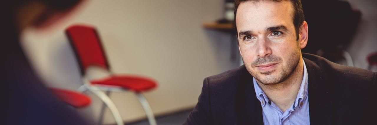 How I Manage Not Knowing What to Do When It's a Trigger for My PTSD man dressed professionally sitting across the table from someone else