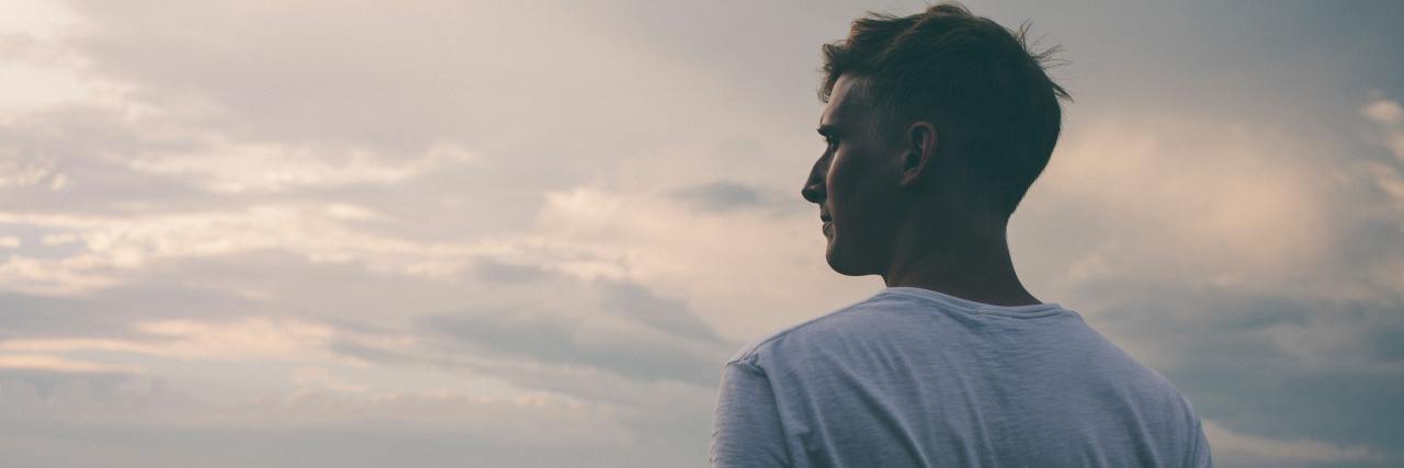 How My Friends and Family Kept Me From Dying by Suicide man in a white t shirt standing looking out into the sky and mountains