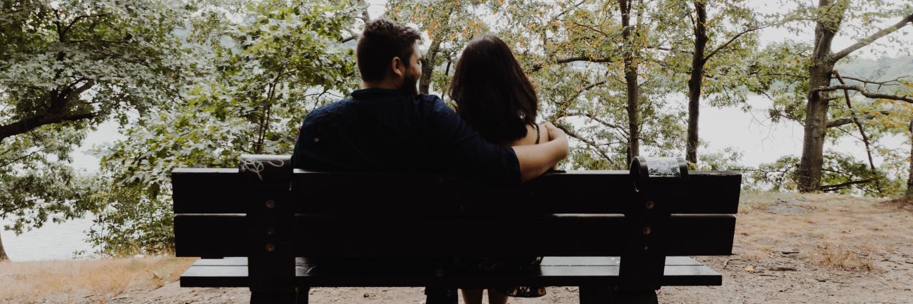 Thank You to My Husband Who Supports Me Through My Depression couple sitting on a bench outside in a park, arms around each other
