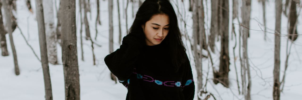I Want to Define My Relationship but Depression Makes Me Afraid photo of young woman standing in snowy woods alone and looking sad, arms wrapped around herself
