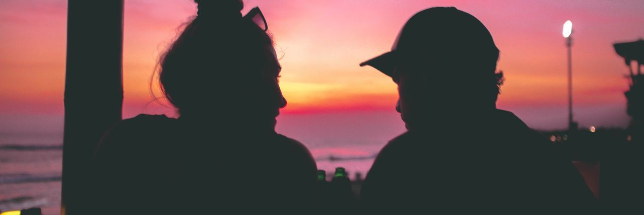 How to Cope With Love Bombing in Relationships photo of couple side by side and silhouetted by vibrant sunset
