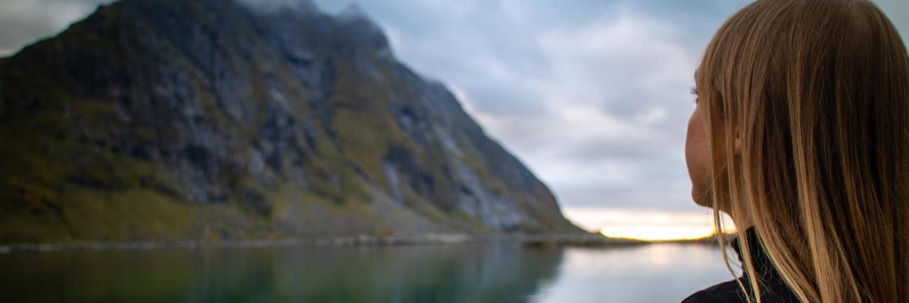 What to Know If You Wonder Who You Will Be Without an Eating Disorder photo of woman taken over shoulder looking at mountains and still water in distance
